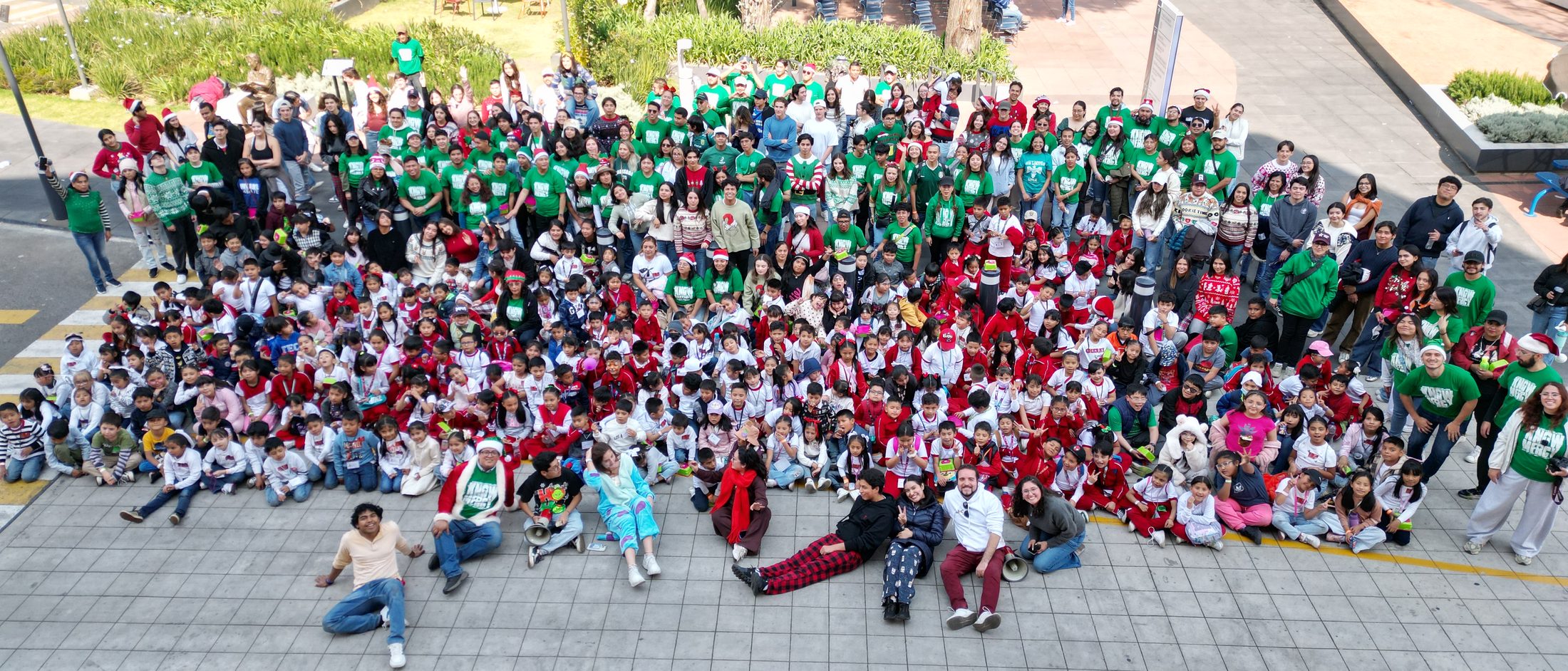 Foto grupal de Posada Tec 2025: voluntarios y niños en la explanada del campus